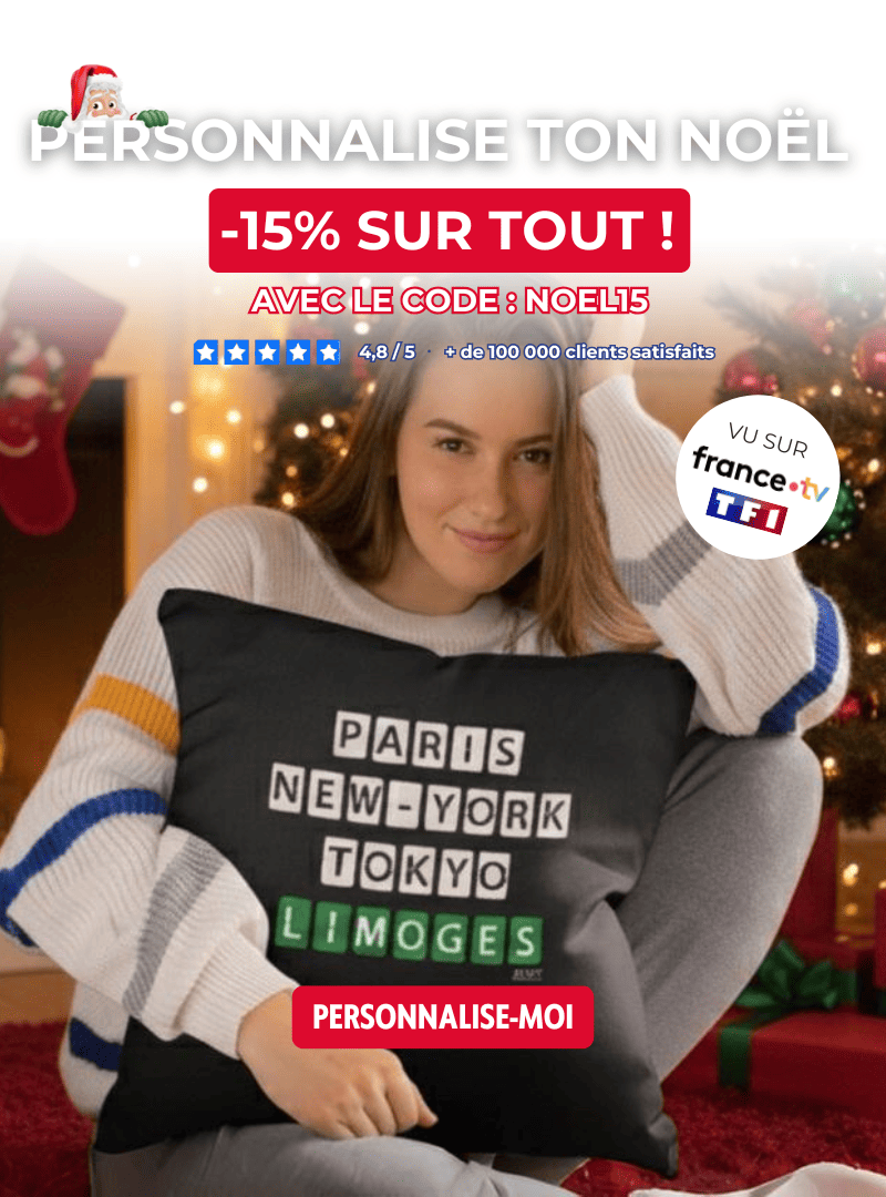 Jeune femme souriante tenant un coussin noir personnalisé avec les villes Paris New York Tokyo Limoges devant un sapin de Noël. Idée de cadeau accessoire personnalisé à sa ville de coeur