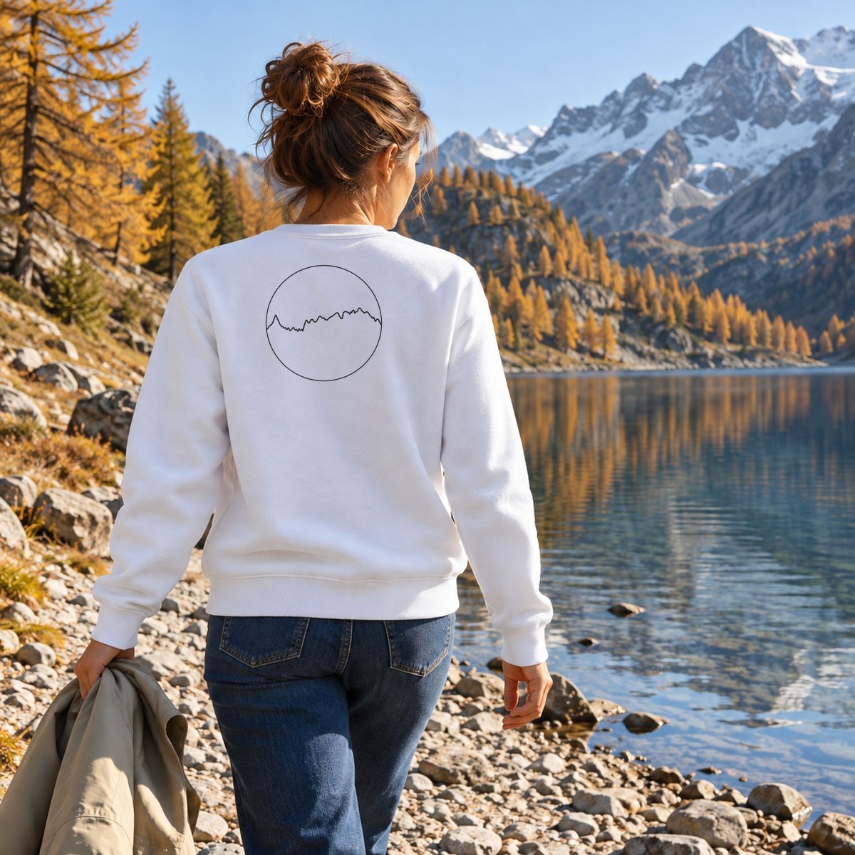 Sweat blanc Les Alpes porté de dos au bord d'un lac de montagne en automne
